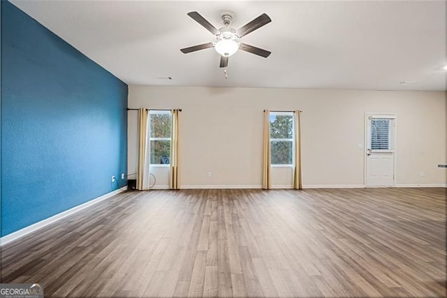 unfurnished room featuring a wealth of natural light, ceiling fan, and hardwood / wood-style flooring