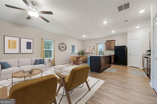 living room with light hardwood / wood-style floors, ceiling fan, and sink