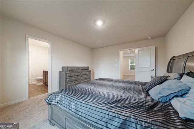 bedroom featuring connected bathroom and light colored carpet