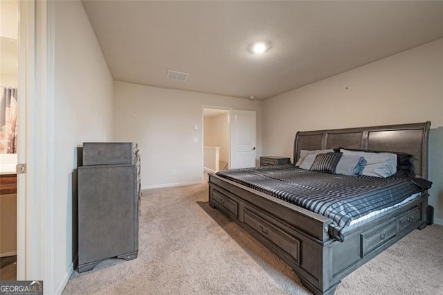 bedroom with light colored carpet and ensuite bath