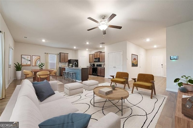 living room featuring ceiling fan and light wood-type flooring