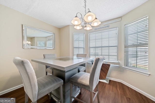 dining space featuring a textured ceiling, dark wood-type flooring, and an inviting chandelier