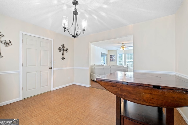 interior space featuring ceiling fan with notable chandelier, light parquet floors, and a textured ceiling