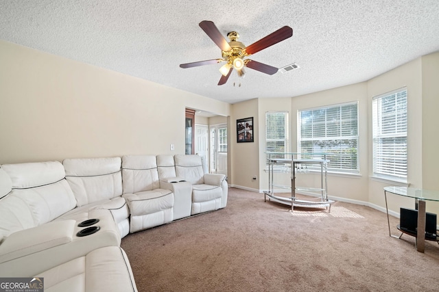 carpeted living room with ceiling fan, a healthy amount of sunlight, and a textured ceiling