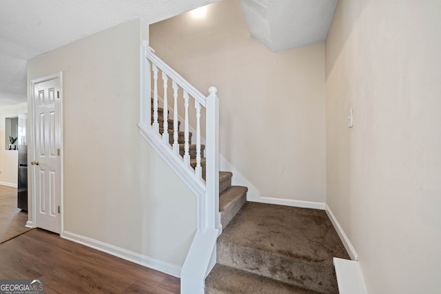 staircase with wood-type flooring and a textured ceiling