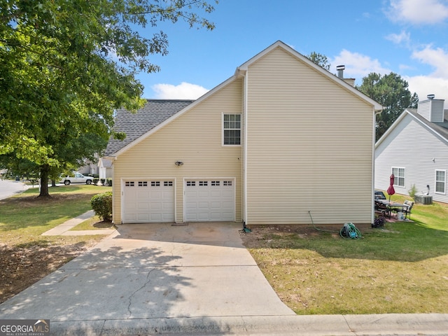 view of side of home with a garage, a yard, and central air condition unit