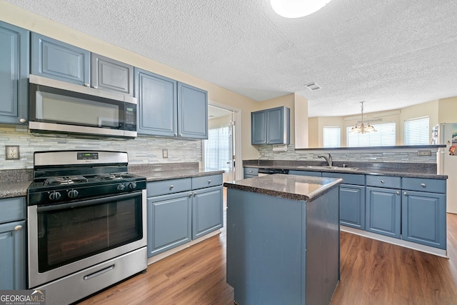 kitchen with a chandelier, a center island, stainless steel appliances, and plenty of natural light