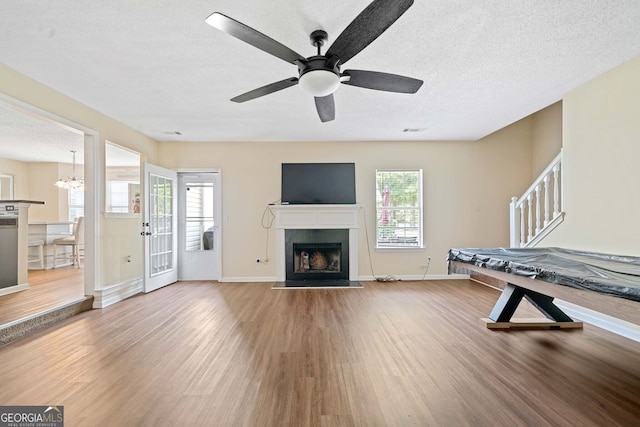 rec room featuring a healthy amount of sunlight, wood-type flooring, and a textured ceiling