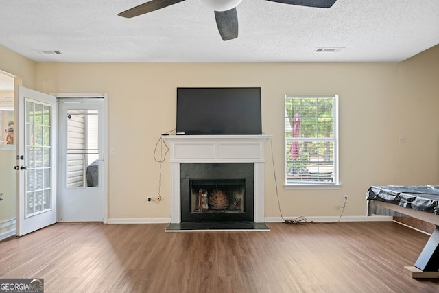 unfurnished living room with ceiling fan, a textured ceiling, and hardwood / wood-style flooring