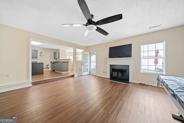 unfurnished living room with ceiling fan, light hardwood / wood-style flooring, and a textured ceiling