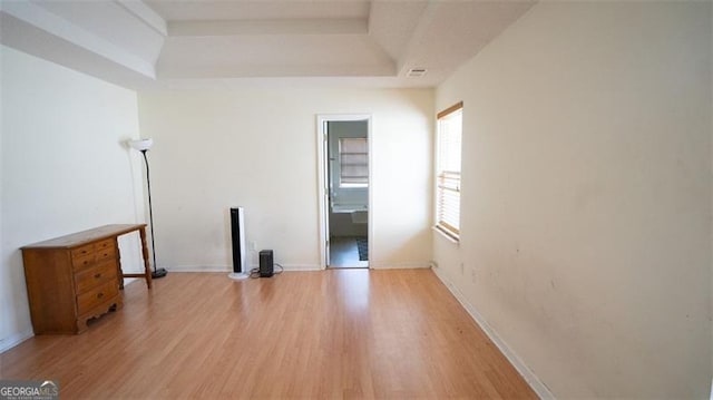 unfurnished room featuring a tray ceiling and light hardwood / wood-style flooring