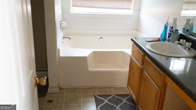 bathroom with tile patterned flooring, vanity, and a bath