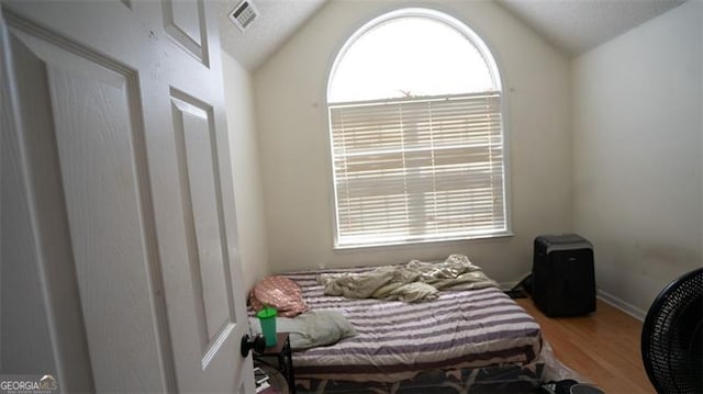 bedroom featuring multiple windows, wood-type flooring, and vaulted ceiling