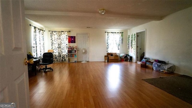 interior space featuring beamed ceiling, a textured ceiling, and hardwood / wood-style flooring