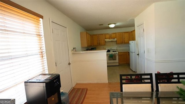 kitchen featuring a textured ceiling, light hardwood / wood-style flooring, and white appliances