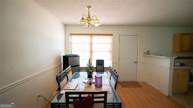 dining room with light hardwood / wood-style floors, a textured ceiling, and a chandelier