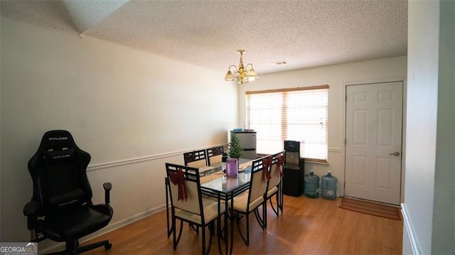 dining area featuring hardwood / wood-style flooring, a notable chandelier, and a textured ceiling