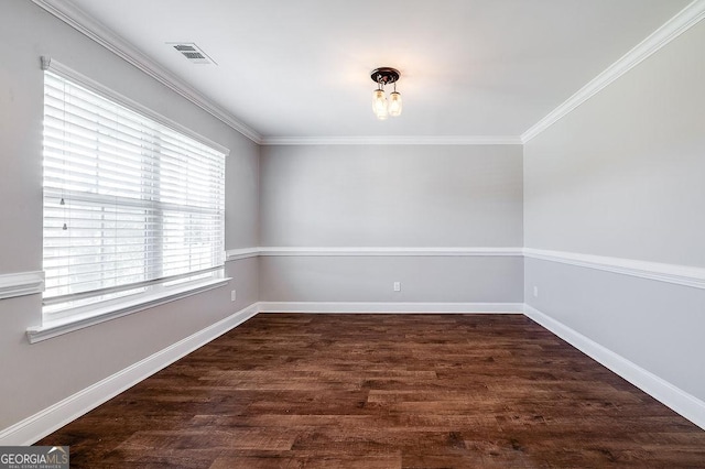 empty room featuring visible vents, ornamental molding, baseboards, and wood finished floors