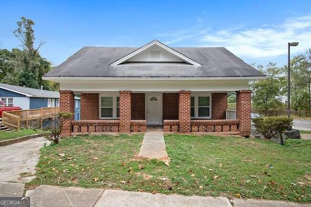 bungalow-style house featuring covered porch and a front yard