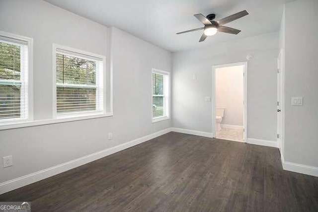 empty room featuring ceiling fan, plenty of natural light, and dark hardwood / wood-style floors