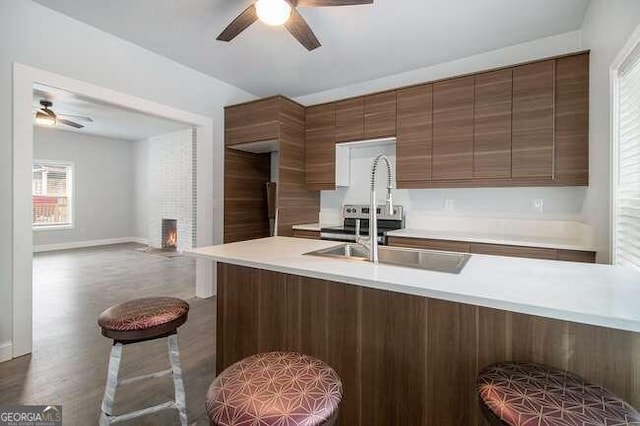 kitchen featuring sink, ceiling fan, a fireplace, dark hardwood / wood-style flooring, and kitchen peninsula