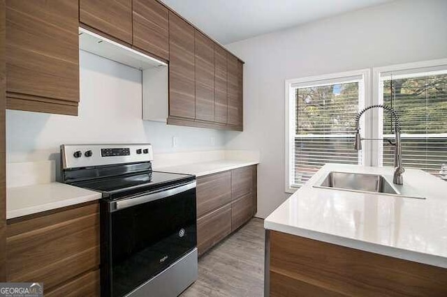 kitchen featuring stainless steel range with electric stovetop, sink, and light hardwood / wood-style flooring