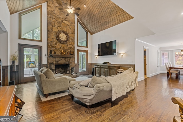 living room featuring high vaulted ceiling, ceiling fan with notable chandelier, a fireplace, wood-type flooring, and wood ceiling