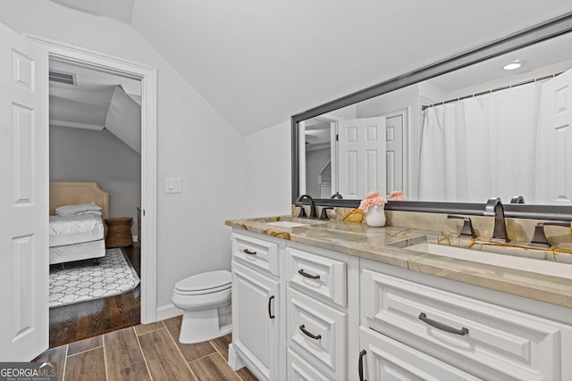 bathroom featuring wood-type flooring, vanity, toilet, and lofted ceiling