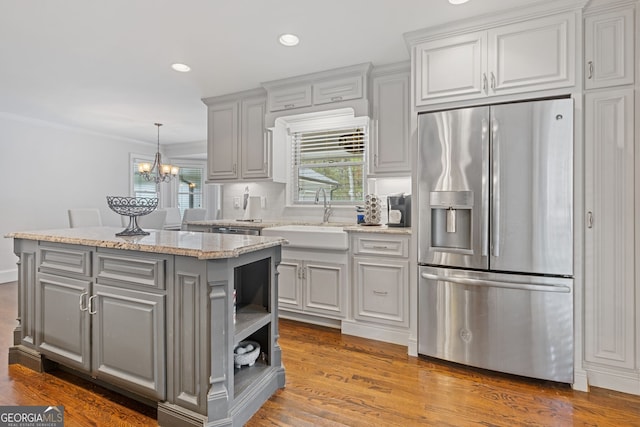 kitchen with sink, stainless steel fridge, wood-type flooring, gray cabinets, and ornamental molding