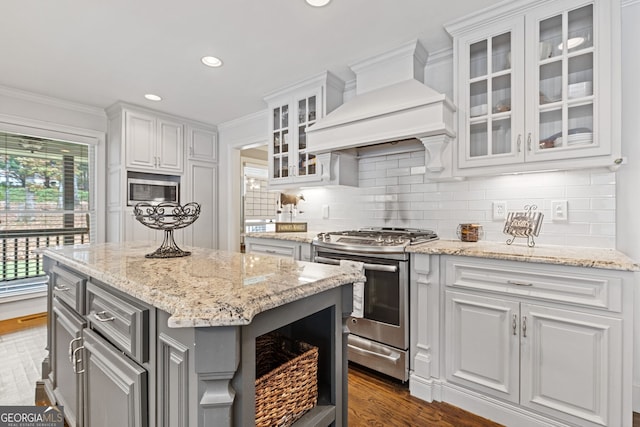 kitchen featuring appliances with stainless steel finishes, a center island, premium range hood, and white cabinetry