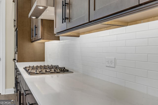 kitchen with stainless steel gas stovetop, decorative backsplash, dark brown cabinetry, and ventilation hood