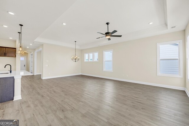 unfurnished living room with sink, light hardwood / wood-style floors, and ceiling fan with notable chandelier