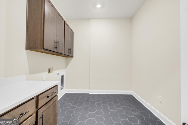 laundry area featuring cabinets, dark tile patterned floors, and electric dryer hookup