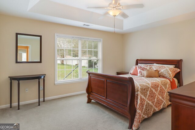 bedroom featuring a raised ceiling, ceiling fan, and light colored carpet