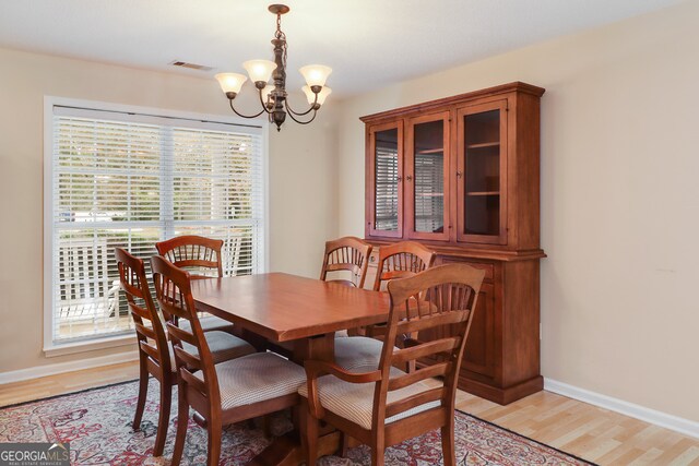 dining space with light hardwood / wood-style flooring and a chandelier