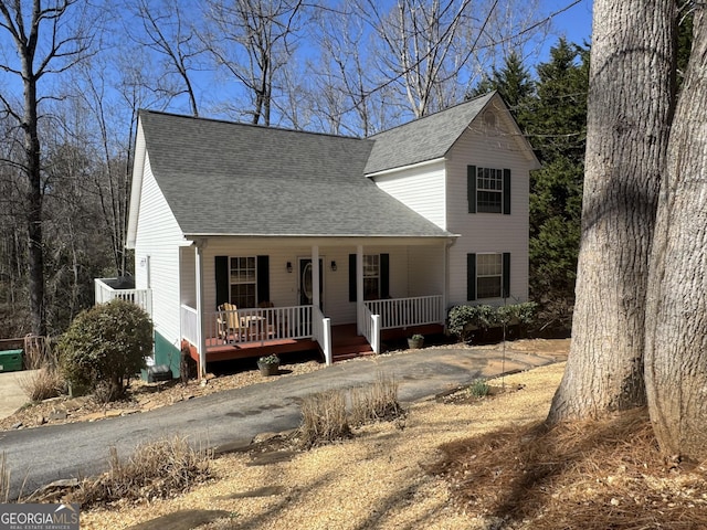 traditional home with covered porch, driveway, and a shingled roof