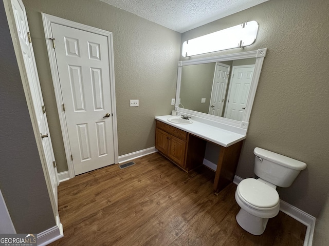 bathroom featuring visible vents, toilet, a textured ceiling, wood finished floors, and vanity
