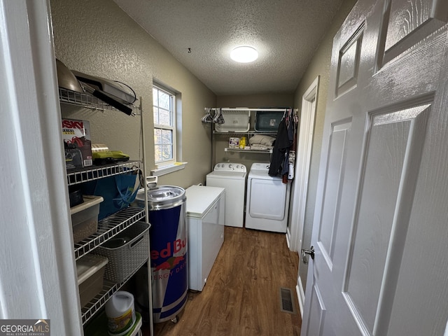 laundry area with dark wood finished floors, laundry area, a textured wall, a textured ceiling, and separate washer and dryer