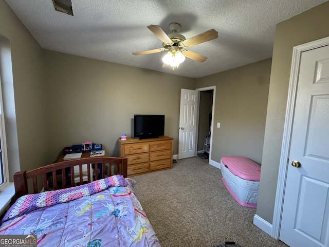 carpeted bedroom featuring ceiling fan and a textured ceiling