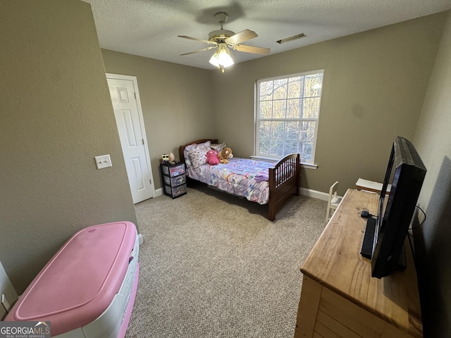 carpeted bedroom featuring visible vents, a ceiling fan, a textured ceiling, baseboards, and a textured wall