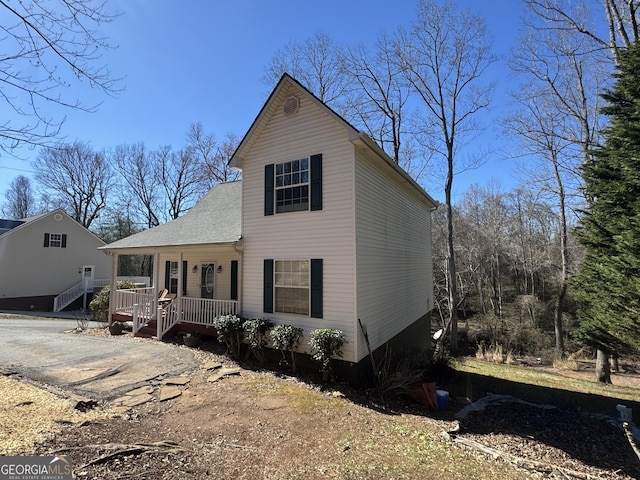 view of front of property featuring roof with shingles, covered porch, and driveway