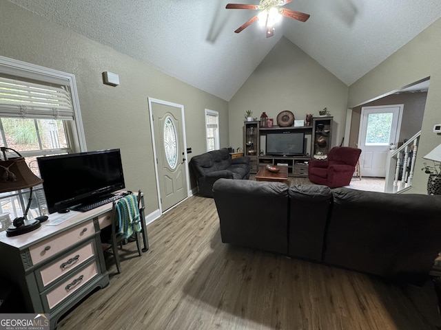 living room with a healthy amount of sunlight, wood finished floors, a ceiling fan, and vaulted ceiling