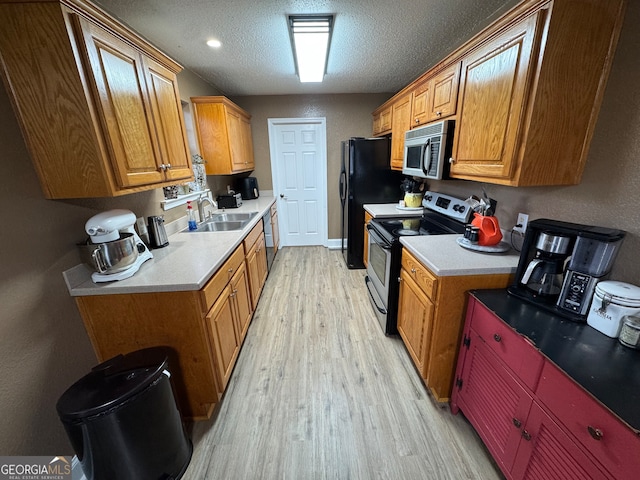 kitchen with sink, stainless steel appliances, a textured ceiling, and light hardwood / wood-style flooring