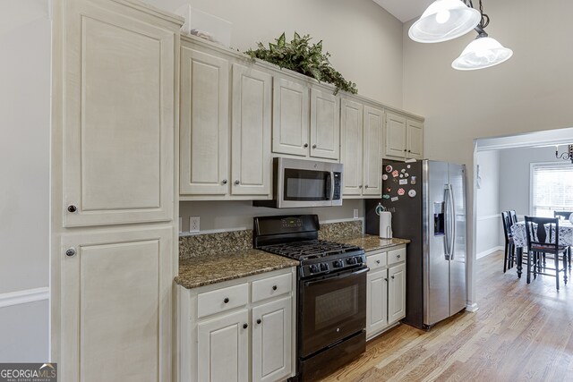 kitchen with pendant lighting, white cabinets, dark stone countertops, appliances with stainless steel finishes, and light hardwood / wood-style floors