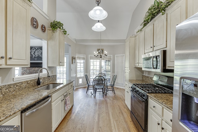 kitchen with sink, plenty of natural light, decorative light fixtures, lofted ceiling, and appliances with stainless steel finishes