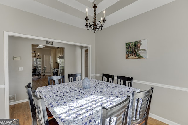 dining area featuring hardwood / wood-style floors and an inviting chandelier