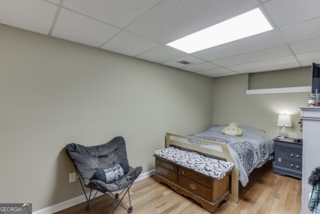 bedroom featuring a drop ceiling and light hardwood / wood-style floors