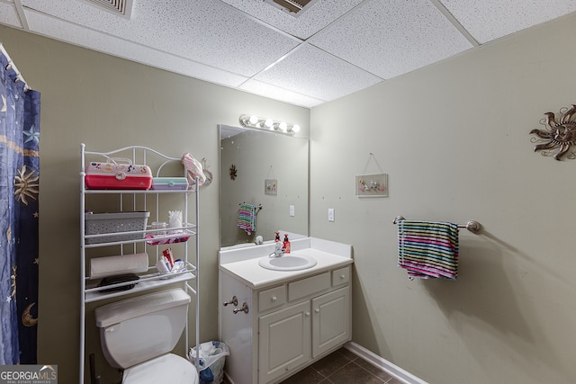 bathroom featuring a paneled ceiling, tile patterned flooring, toilet, and vanity