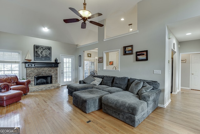 living room featuring a fireplace, light hardwood / wood-style floors, ceiling fan, and a healthy amount of sunlight