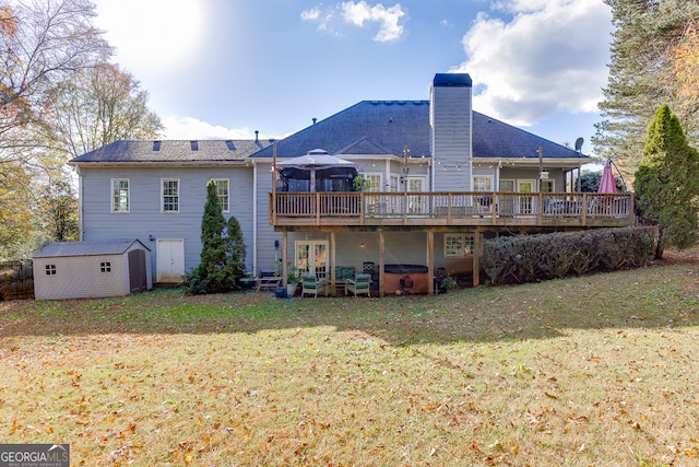 rear view of house with a lawn, a storage shed, a jacuzzi, a gazebo, and a deck